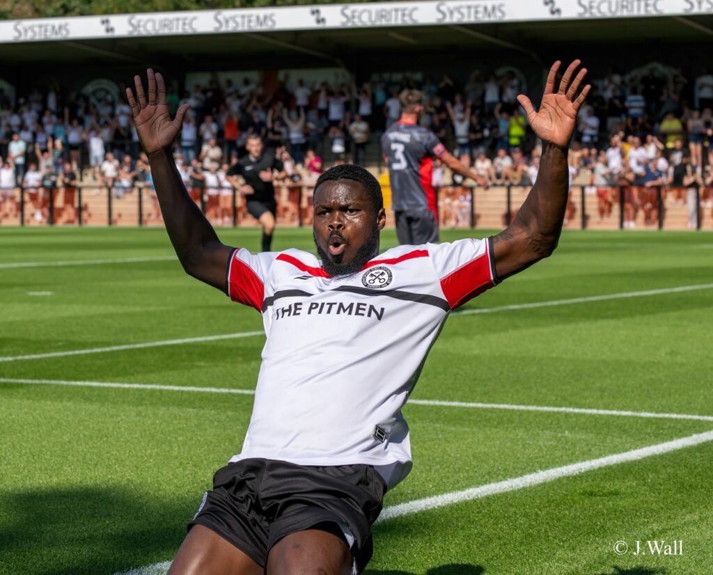 Ahkeem Rose celebrating a goal on his knees and hands up.