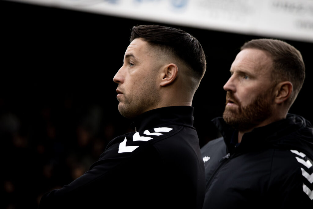 Two managers looking at squad on the field